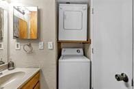 laundry area with stacked washing maching and dryer and electric panel