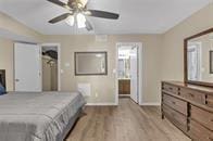 bedroom with ceiling fan, connected bathroom, and light wood-type flooring