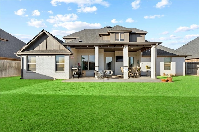 rear view of property with a yard, brick siding, fence, and a patio