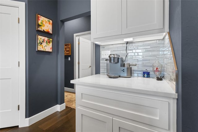 kitchen featuring tasteful backsplash, baseboards, light countertops, white cabinetry, and dark wood finished floors