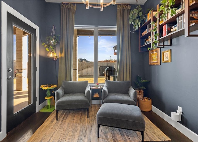 living area featuring baseboards, an inviting chandelier, and wood finished floors