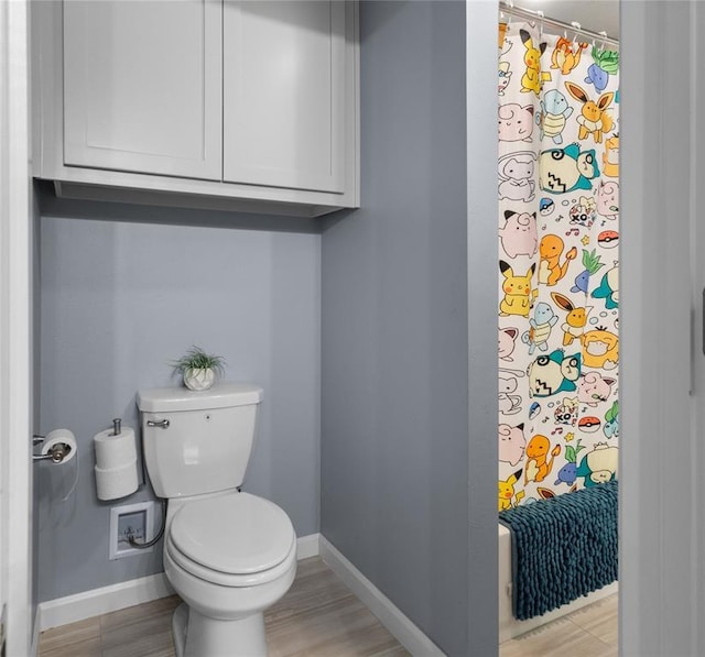 bathroom with baseboards, a shower with curtain, and toilet