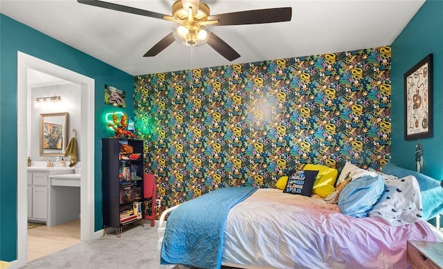 carpeted bedroom with a ceiling fan, connected bathroom, an accent wall, and wallpapered walls