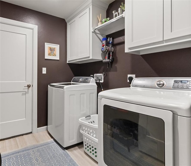 laundry area with independent washer and dryer, light wood-style floors, and cabinet space