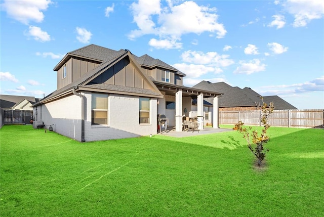 rear view of house featuring a patio, board and batten siding, a fenced backyard, and a lawn