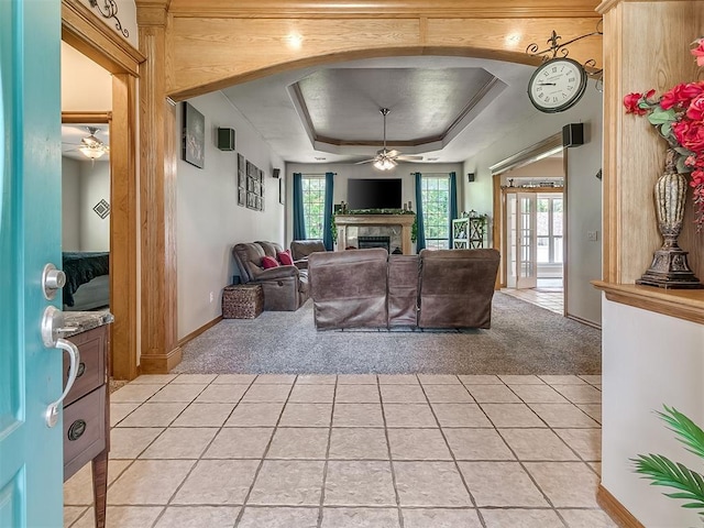 living room with a tray ceiling, light colored carpet, and ceiling fan