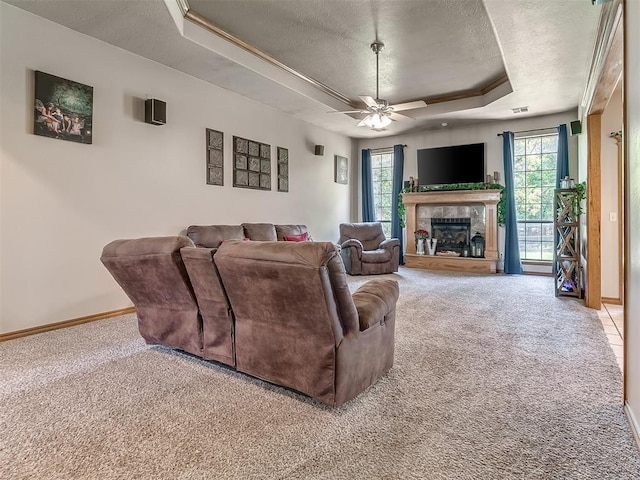 living room with ceiling fan, light colored carpet, a textured ceiling, and a tray ceiling