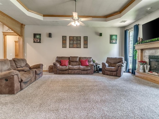 living room with a premium fireplace, crown molding, carpet floors, and a raised ceiling