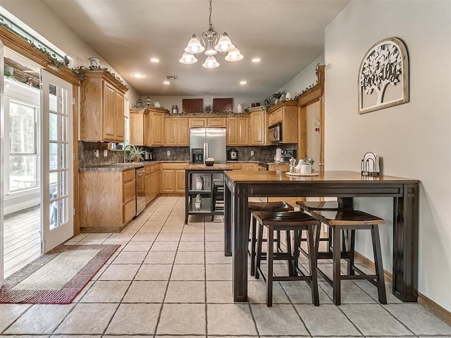 kitchen featuring appliances with stainless steel finishes, sink, a kitchen breakfast bar, decorative backsplash, and light tile patterned floors