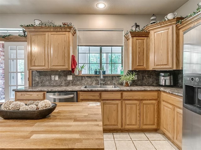 kitchen with tasteful backsplash, stainless steel appliances, sink, and wooden counters