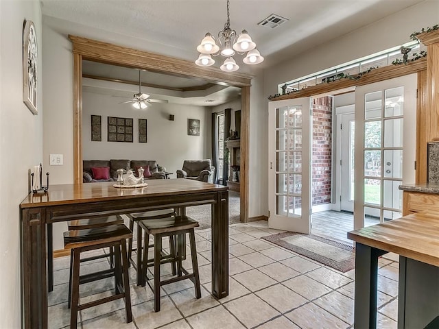 tiled dining area with a raised ceiling and ceiling fan with notable chandelier