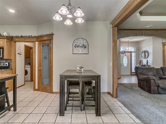 dining area with washer / dryer, light carpet, and a notable chandelier