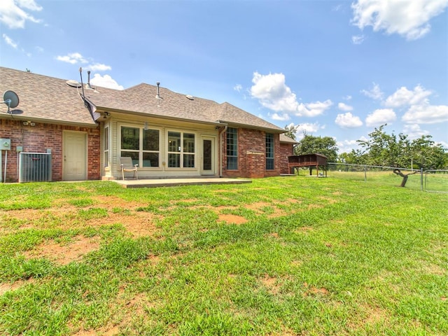 rear view of house featuring a yard, central air condition unit, and a patio area