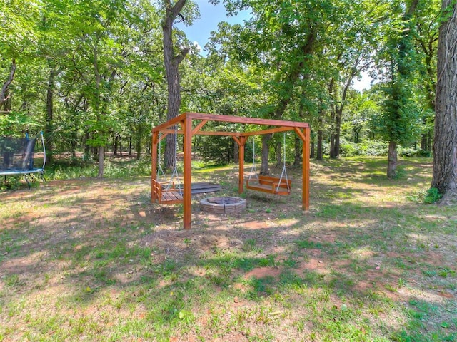 view of yard featuring a fire pit and a trampoline