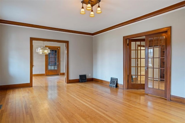 spare room featuring french doors, a chandelier, and light hardwood / wood-style flooring