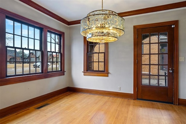 unfurnished dining area with a notable chandelier, ornamental molding, and light hardwood / wood-style floors