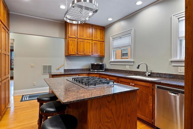 kitchen featuring a breakfast bar, sink, dark stone counters, a center island, and stainless steel appliances