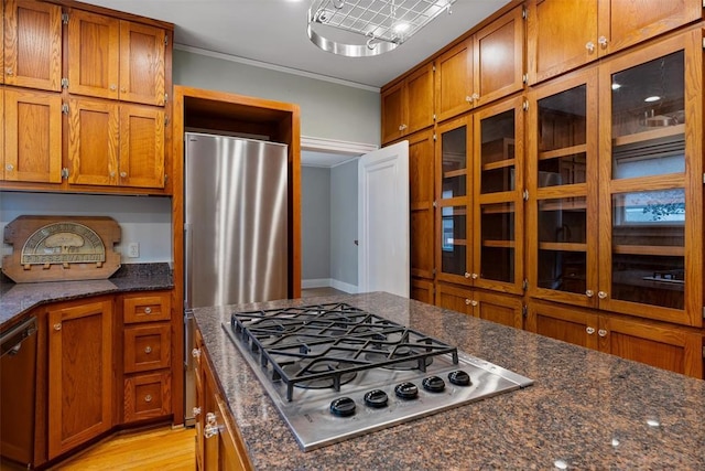 kitchen featuring dark stone countertops, light wood-type flooring, ornamental molding, and appliances with stainless steel finishes