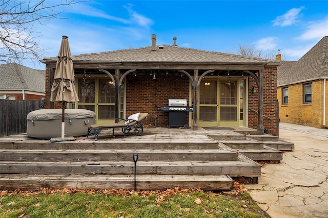 rear view of house with a hot tub and a deck