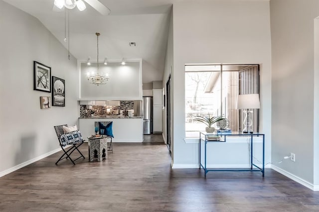 interior space with dark hardwood / wood-style flooring, ceiling fan with notable chandelier, and high vaulted ceiling