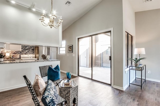 dining space with an inviting chandelier, high vaulted ceiling, and hardwood / wood-style floors