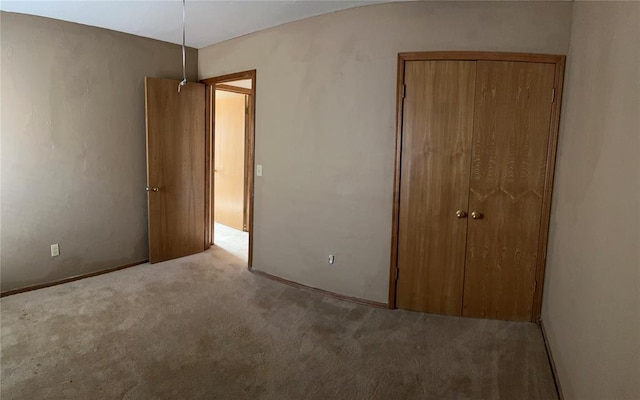 unfurnished bedroom featuring light colored carpet and a closet