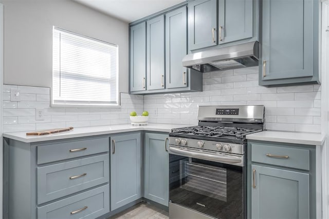 kitchen featuring tasteful backsplash, stainless steel gas range, and gray cabinetry