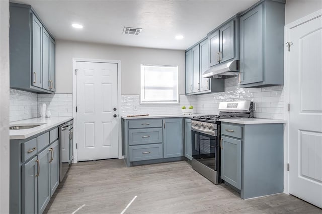 kitchen featuring tasteful backsplash, appliances with stainless steel finishes, and light hardwood / wood-style flooring