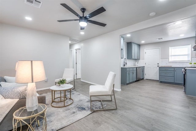 living room featuring ceiling fan, sink, and light hardwood / wood-style floors