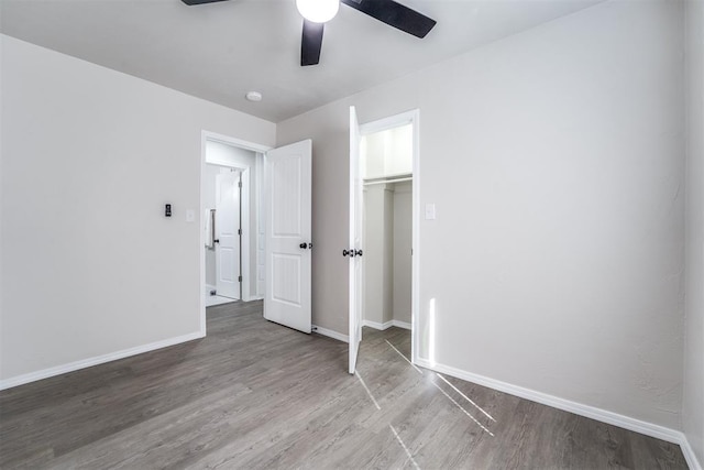 unfurnished bedroom featuring ceiling fan, wood-type flooring, and a closet