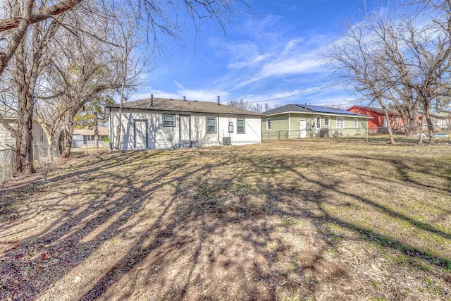 rear view of property featuring central AC unit and a lawn