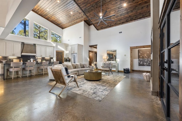 living room featuring ceiling fan, a high ceiling, and wooden ceiling