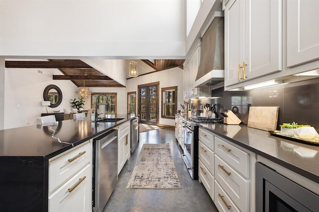 kitchen with sink, appliances with stainless steel finishes, lofted ceiling with beams, white cabinets, and wall chimney exhaust hood