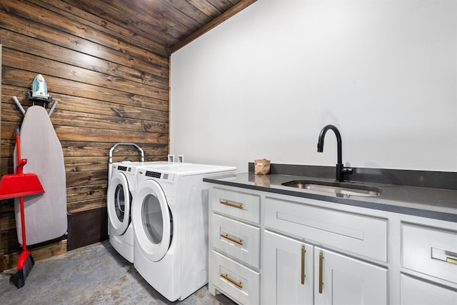 laundry room with sink, wood walls, wood ceiling, cabinets, and separate washer and dryer