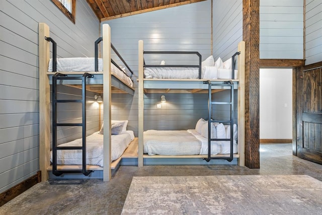 unfurnished bedroom with high vaulted ceiling, concrete floors, and wood walls