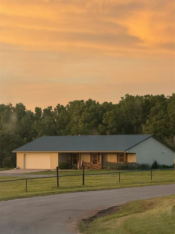 728 S Carol St, Carnegie, OK 73015 - view of front of house with asphalt driveway, an attached garage, and metal roof