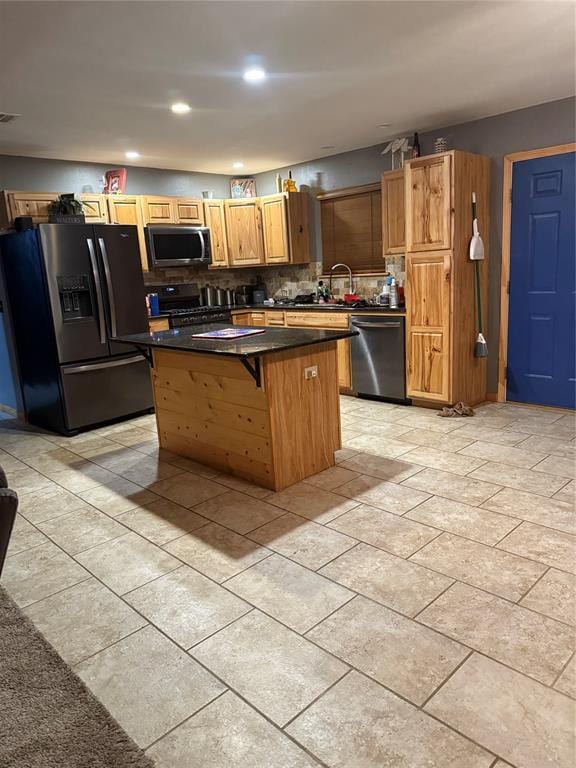 728 S Carol St, Carnegie, OK 73015 - kitchen with appliances with stainless steel finishes, a kitchen island, dark countertops, a kitchen bar, and backsplash