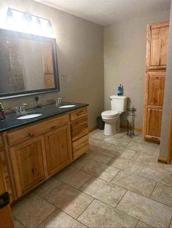 728 S Carol St, Carnegie, OK 73015 - bathroom with double vanity, toilet, and baseboards