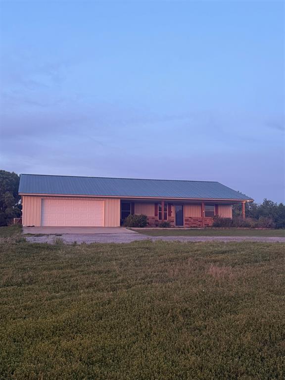 728 S Carol St, Carnegie, OK 73015 - view of front of home featuring a front lawn, metal roof, an attached garage, and driveway