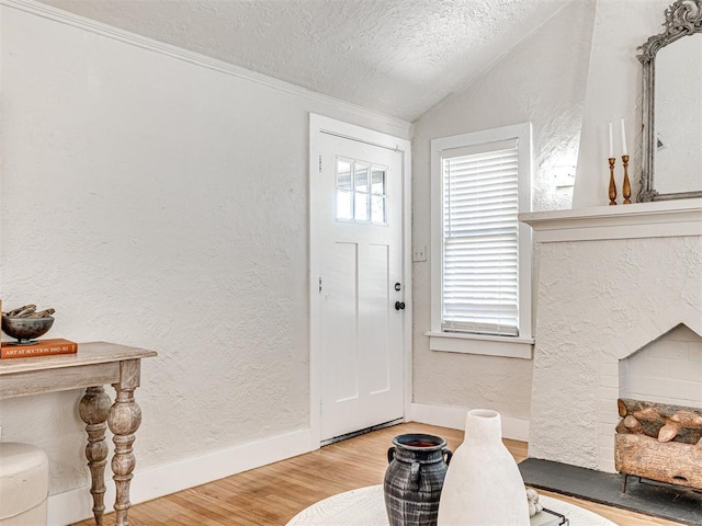 foyer entrance with hardwood / wood-style flooring, lofted ceiling, and a textured ceiling