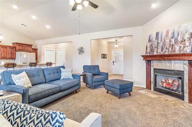 carpeted living room featuring a tiled fireplace, high vaulted ceiling, and ceiling fan