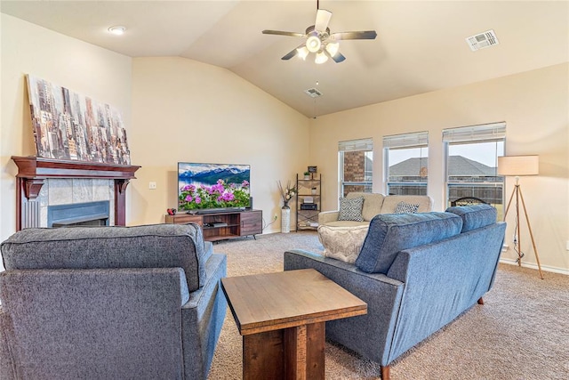 carpeted living room featuring ceiling fan, lofted ceiling, and a tiled fireplace