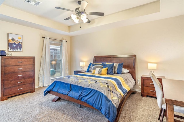 carpeted bedroom with ceiling fan and a raised ceiling