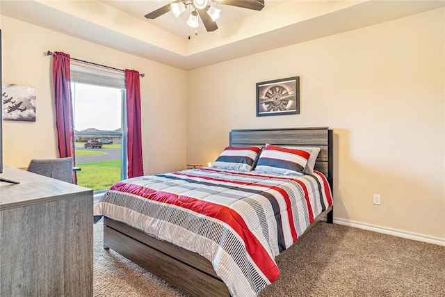 carpeted bedroom featuring ceiling fan and a tray ceiling