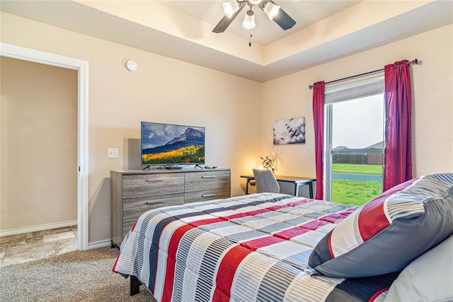 carpeted bedroom featuring ceiling fan and a raised ceiling