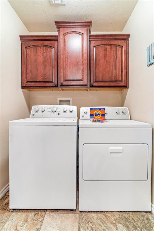 clothes washing area featuring cabinets, washer and dryer, and a textured ceiling