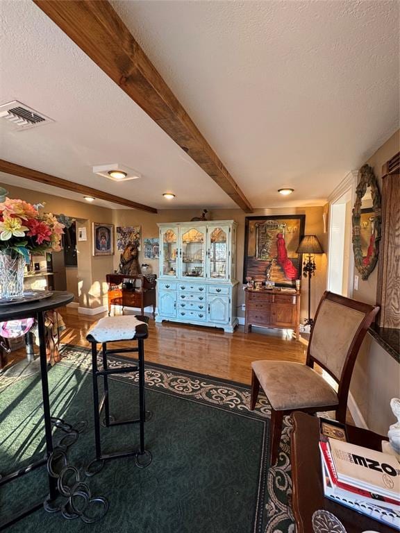 living room with a textured ceiling, hardwood / wood-style floors, and beam ceiling