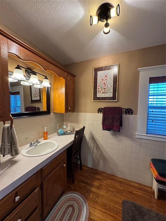 bathroom featuring hardwood / wood-style flooring, vanity, tile walls, and a textured ceiling