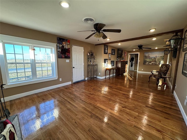 unfurnished living room featuring ceiling fan and dark wood-type flooring