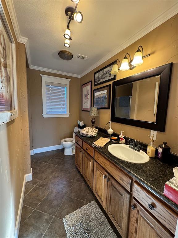 bathroom with toilet, vanity, tile patterned flooring, and crown molding